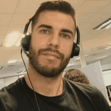 a man with a beard is wearing headphones and a black shirt