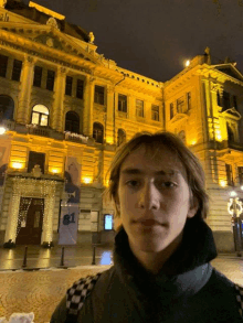 a young man stands in front of a building that says 81 on it