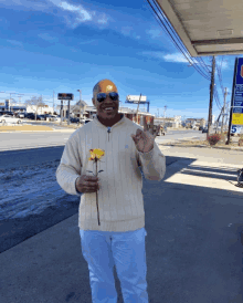 a man holds a flower in front of a gas station