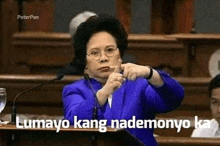 a woman in a blue suit is giving a speech in front of a microphone in a parliament .