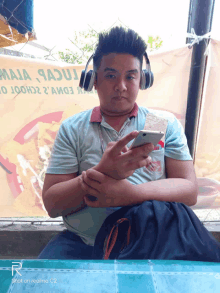 a man wearing headphones sits in front of a sign that says maja