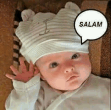 a baby wearing a hat with a speech bubble that says salam is waving .