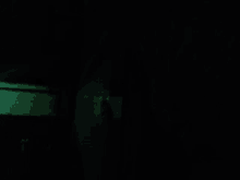 a dark room with a green light coming out of the window