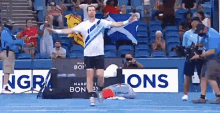 a man holding a scottish flag on a tennis court in front of a sign that says ' sions '