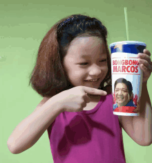 a little girl points at a bongbong marcos cup with a straw