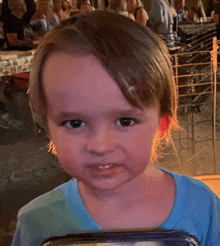 a young boy with a blue shirt on is looking at the camera