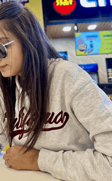 a girl wearing sunglasses and a sweatshirt that says california