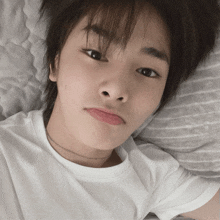 a young boy laying on a bed with a white shirt on