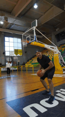 a man is dribbling a basketball on a basketball court with a sign that says ' no smoking ' on it