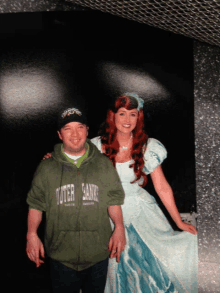 a man in a green outer banks sweatshirt poses with a princess