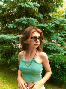 a girl wearing sunglasses and a green tank top