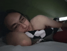 a man wearing glasses is laying in bed