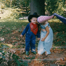 a little boy in a cowboy hat is standing next to a little girl in a fairy costume