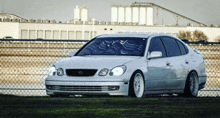 a silver lexus car is parked in front of a fence