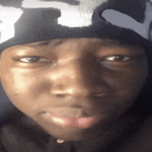 a close up of a person 's face wearing a black and white hat with the letter t on it