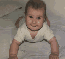 a baby in a white shirt is crawling on its stomach