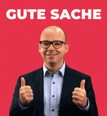 a man in a suit giving a thumbs up in front of a red background that says gute sache