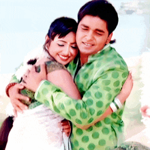 a man in a green polka dot shirt is hugging a smiling woman