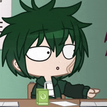 a boy with green hair sits at a desk