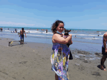 a woman wearing a face mask holds a small dog on a beach