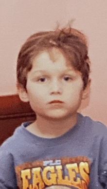 a young boy wearing a blue eagles shirt