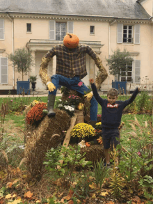 a boy wearing a levi 's sweatshirt is standing next to a scarecrow