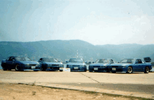 four blue cars are parked next to each other on a sunny day