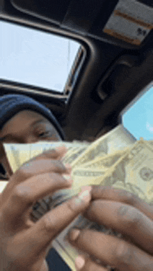 a man in a car is holding a bunch of money in his hands .