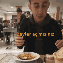 a man sitting at a table with a bowl of food and the words beyler ac misiniz written on the bottom