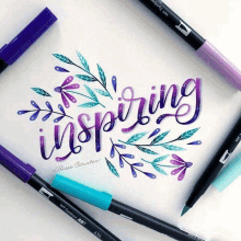 the word inspiring is written on a piece of paper surrounded by different colored pens