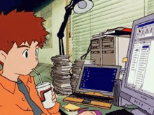 a boy is drinking from a cup while sitting in front of a computer monitor .