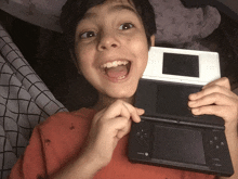 a young boy is holding a black and white nintendo ds game console