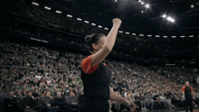 a woman stands on a basketball court in front of a crowd with a sign that says audi on it