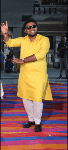 a man in a yellow shirt and white pants is standing on a colorful mat