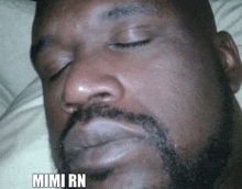 a man with a beard is sleeping with his eyes closed and the word mimi rn is on the bottom of his face .