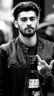 a black and white photo of a man with a beard and a leather jacket giving the middle finger .