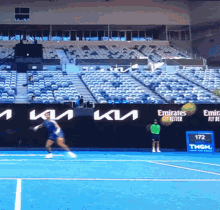 a tennis player is swinging a racket on a court with emirates fly better written on the wall behind him