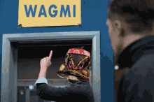 a man points to a sign that says wagmi on it