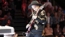 a man is playing a guitar in front of a crowd .