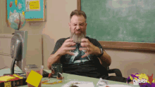 a man with a beard is sitting at a desk in front of a blackboard with the word podcast on it