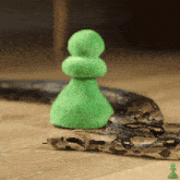 a snake is laying on the floor next to a green pawn