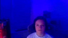 a young boy is sitting in a chair in front of a computer screen with blue lights behind him .