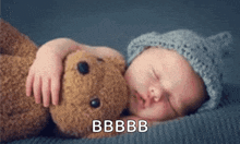 a baby is sleeping next to a teddy bear and the baby is wearing a knitted hat and holding the teddy bear .