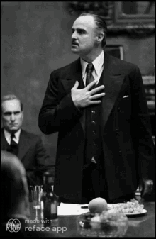 a man in a suit and tie is standing in front of a table with a plate of fruit on it