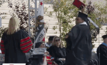 a man in a graduation cap and gown holds up a diploma in front of a flag that says california