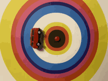 a red toy car is in the middle of a rainbow colored target