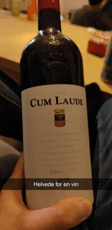 someone is holding a bottle of cum laude toscana wine