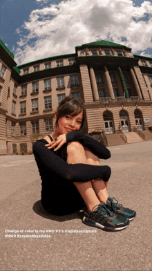 a woman is kneeling down in front of a large building with a caption that says change of color in my nmd v3 's