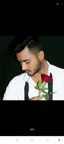 a man in a white shirt and black tie holding a red rose