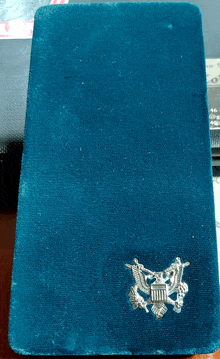 a blue velvet wallet with a silver emblem on the front